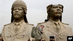 FILE - U.S. soldiers walk past two gigantic status of former Iraqi President Saddam Hussein in Baghdad, March 20, 2009.