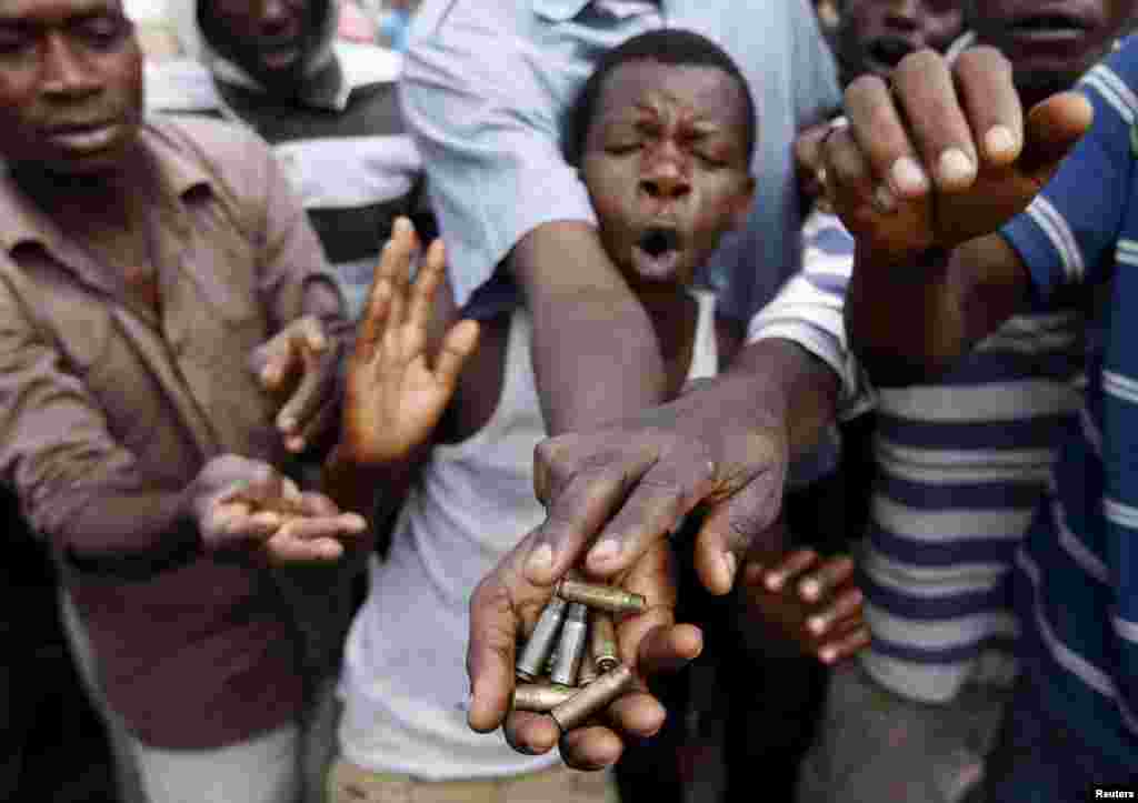 Manifestantes mostram casos de bala em Bujumbura, Burundi. Ao protestar contra Presidente do Burundi Pierre Nkurunziza e sua tentatíva por uma terceiro mandato, os policias usam gâs lacrimogêneo e batem nas manifestantes numa ressurgimento de agitaçâo que tem deixado medo de conflito étnico nos Grandes Largos da Àfrica.