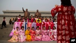North Korean women in traditional dresses pose for a souvenir photograph in front of bronze statues of the late leaders Kim Il Sung and Kim Jong Il at Munsu Hill in Pyongyang on Tuesday, April 15, 2014.