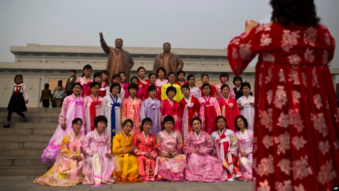North Korean women in traditional dresses pose for a souvenir photograph in front of bronze statues of the late leaders Kim Il Sung and Kim Jong Il at Munsu Hill in Pyongyang on Tuesday, April 15, 2014.