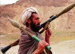 FILE - A Taliban fighter walks with a Russian made RPG7 on the front line area in Gorband valley, 150 km northwest of Kabul, Afghanistan, May 3, 1997.