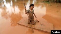 A girl uses a mattress as a raft during the flood after the Xe Pian Xe Namnoy hydropower dam collapsed in Attapeu province, Laos July 26, 2018.