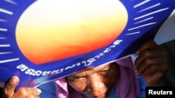 A woman holds a poster bearing the logo of the Cambodian National Rescue Party (CNRP) during a protest demanding a free and fair general election, at the Freedom Park in Phnom Penh, file photo. 