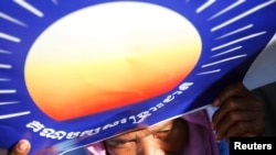 A woman holds a poster bearing the logo of the Cambodian National Rescue Party (CNRP) during a protest demanding a free and fair general election, May 20, 2013.