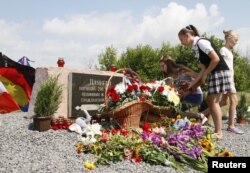 FILE - People gather near a monument for the victims of the Malaysia Airlines flight MH17 plane crash to mark the fourth anniversary of the accident near the village of Hrabove (Grabovo) in Donetsk Region, Ukraine, July 17, 2018.