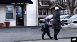 A woman and child walk past the Lucky Star Body Work massage spa in Stoneham, Mass., Monday, Feb. 25, 2019. The massage spa, which is located between the town library and a church, was shut down twice in 2018 for human sex trafficking. (AP Photo)