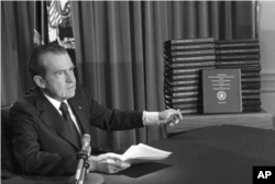 FILE - President Richard M. Nixon points to transcripts of White House tapes, April 29, 1974.