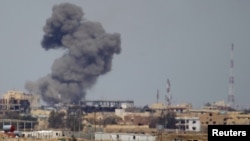 FILE - A plume of smoke rises above a building after an airstrike by the U.S.-led coalition battling the Islamic State group in Tikrit, Iraq, March 27, 2015. 