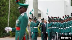 Le président français Francois Hollande inspecte la garde d'honneur à la villa présidentielle à Abuja, Nigeria, le 14 mai 2016.