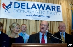 Sen. Chris Coons D-Del., accompanied by his wife Annie, left, and family, speaks to supporters after winning his re-election bid for the Senate, Tuesday, Nov. 4, 2014, during election night party in Newark, Del.