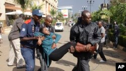 Petugas keamanan membawa korban luka akibat serangan bersenjata di Westgate Mall di Nairobi, Kenya (September 2013) yang dilakukan anggota kelompok militan al-Shabab.