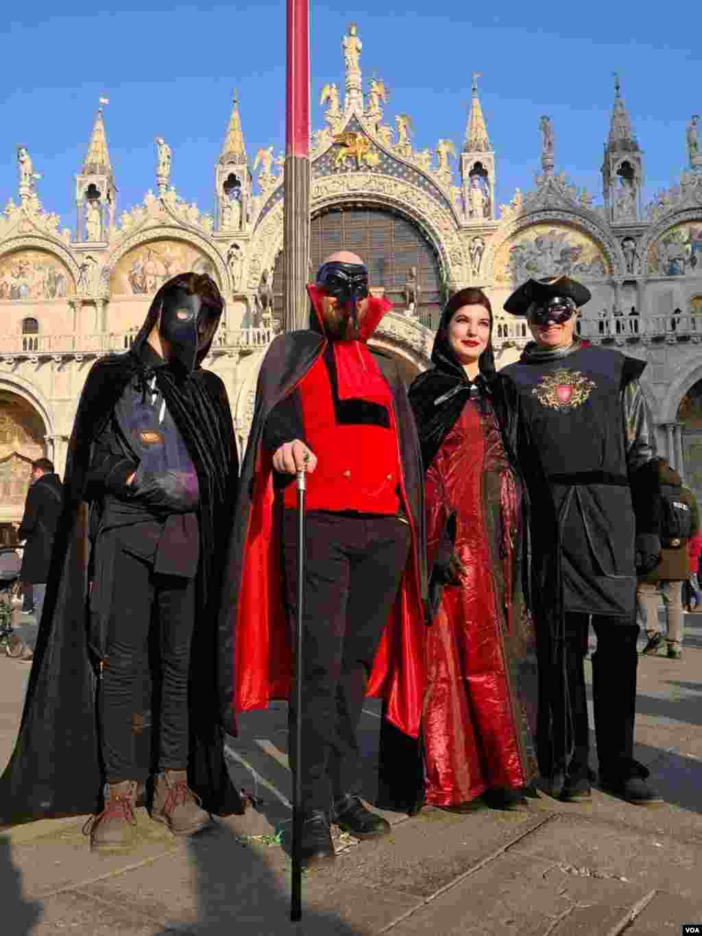 People pose in front of Saint Mark’s Basilica on opening day of the Venice Carnival, in Venice, Italy, Feb. 8, 2020.
