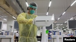 An operator wearing personal protective equipment wipes down the coronavirus disease swab test robot called SwabBot during a demonstration in Singapore Sept. 25, 2020. 