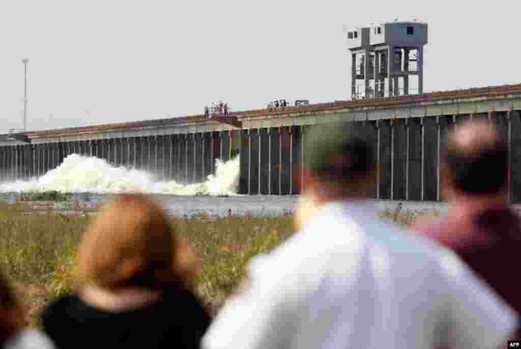 People watch as water diverted from the Mississippi River spills through a bay in the Morganza Spillway in Morganza, La., on Saturday. A steel, 10-ton floodgate was slowly raised Saturday for the first time in nearly four decades, unleashing a torrent of 