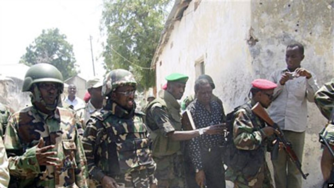 Somali president Sheik Sharif Sheik Ahmed (2nd L) comes to see where police displayed the bodies of four al-Shabab fighters killed during fighting in Mogadishu, Mar 22 2011