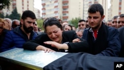 A relative cries over the coffin of Uygar Coskun, 32, killed in Saturday's bombing attacks, during his funeral, in Ankara, Turkey, Oct. 12, 2015.