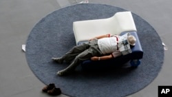 A visitor takes a nap on a couch at the National Museum of Emerging Science and Innovation, in Tokyo.