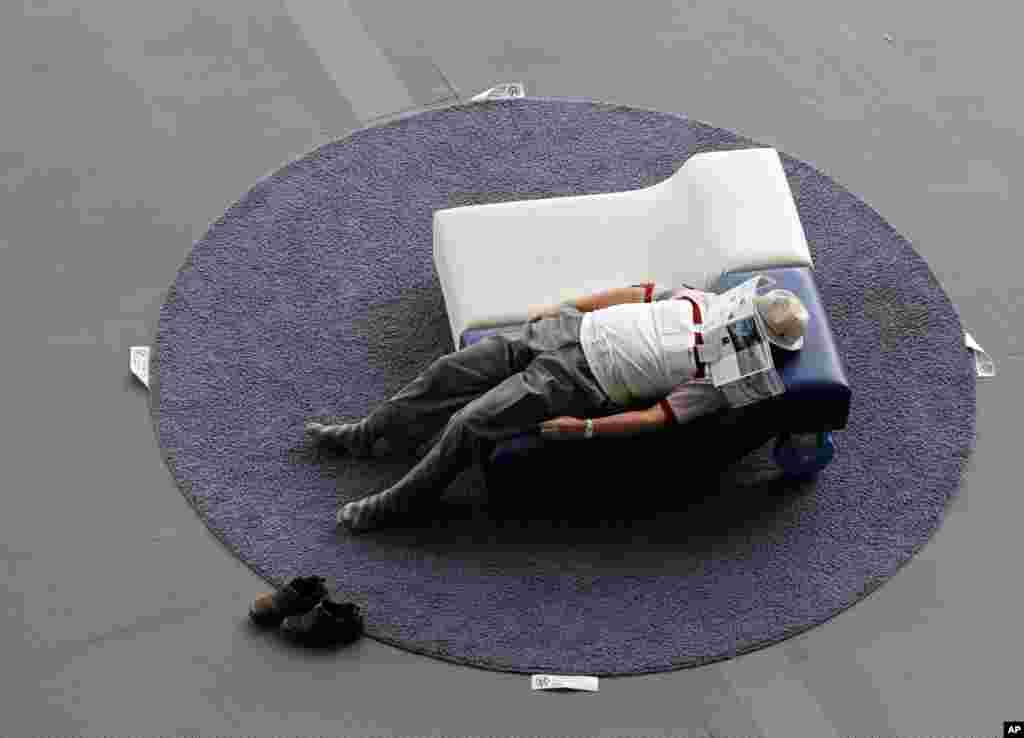 A visitor takes a nap on a couch at the National Museum of Emerging Science and Innovation, in Tokyo, Japan.