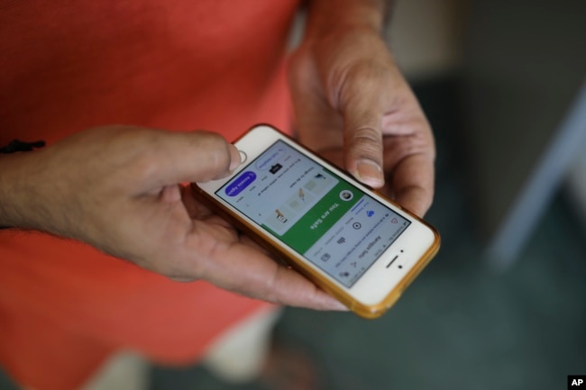 In this Thursday, May 7, 2020 photo, an Indian man uses an app on his mobile phone in New Delhi, India. (AP Photo/Altaf Qadri)