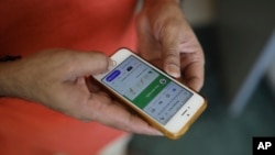 In this Thursday, May 7, 2020 photo, an Indian man uses Aarogya Setu app on his mobile phone in New Delhi, India. (AP Photo/Altaf Qadri)