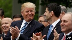 FILE - President Donald Trump, surrounded by Republican congressmen, acknowledges House Speaker Paul Ryan in the Rose Garden of the White House in Washington, May 4, 2017, after the House pushed through a health care bill. With midterm elections looming in 2018, Republican members of the House are pondering how far to distance themselves from Trump.