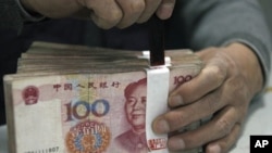 An employee seals a stack of yuan banknotes at a branch of Industrial and Commercial Bank of China in Huaibei, Anhui province, April 6, 2011