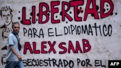 Un hombre pasa junto a un grafiti que reza "libertad para el diplomático Alex Saab, secuestrado por el gobierno de Cabo Verde" en Caracas, el 23 de febrero de 2021.