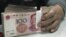 An employee seals a stack of yuan banknotes at a branch of Industrial and Commercial Bank of China in Huaibei, Anhui province, April 6, 2011