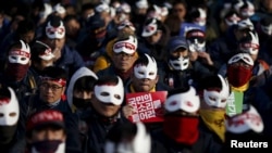 Masked protesters participate in an anti-government rally in central Seoul, South Korea, Dec. 5, 2015. The sign in center reads: "Listen to people's voice."