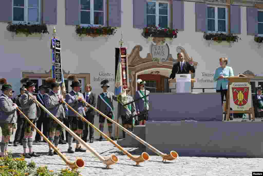 Pemain Alpenhorn berdiri di depan Presiden AS Barack Obama sementara ia dan Kanselir Jerman Angela Merkel berpidato di desa Bavaria, Kruen, Jerman.