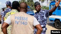 A policeman gestures at a journalist during a sit-in near the presidency to protest against a new media law in Lome, Togo, March 14, 2013. 