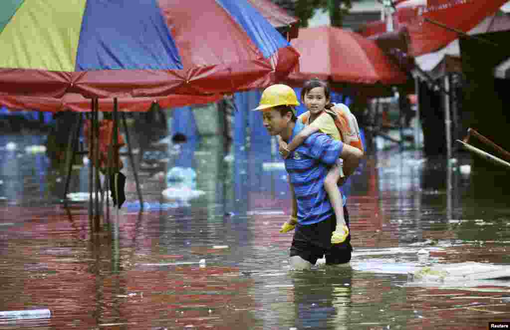 A man carries a girl on his back as he wades through a flooded street after heavy rainfalls hit Changsha, Hunan province, China.