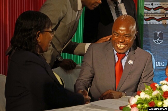 Opposition Malawi Congress Party General Secretary, Eisenhower Mkaka, cracks jokes with MEC chairperson Jane Ansah as he signed a code of conduct,Tuesday in Lilongwe.