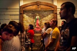 FILE - Worshippers pray next to a shrine to Our Lady of Guadalupe, the patroness of the Americas especially revered by Mexicans, during Mass at the St. John Paul II Pastoral Center in Gainesville, Georgia, Aug. 9, 2015.