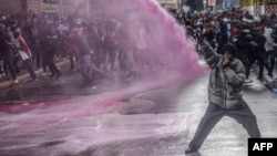 A protester reacts as Kenyan police officers spray water to disperse the crowd during a demonstration against tax increases in downtown Nairoibi on June 20, 2024.