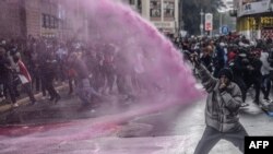 Um manifestante reage enquanto os agentes da polícia queniana pulverizam água para dispersar a multidão durante uma manifestação contra o aumento dos impostos no centro de Nairoibi, a 20 de junho de 2024.