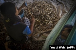 Seorang anak perempuan yang bekerja sambil menjaga bayinya. Laju perkawinan anak di Indonesia masih tinggi meski pemerintah telah menyusun sejumlah aturan.