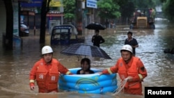 Petugas penyelamat mengevakuasi seorang warga yang terkena banjir akibat hujan lebat di Pingxiang, provinsi Jiangxi, China 9 Juli 2019. 