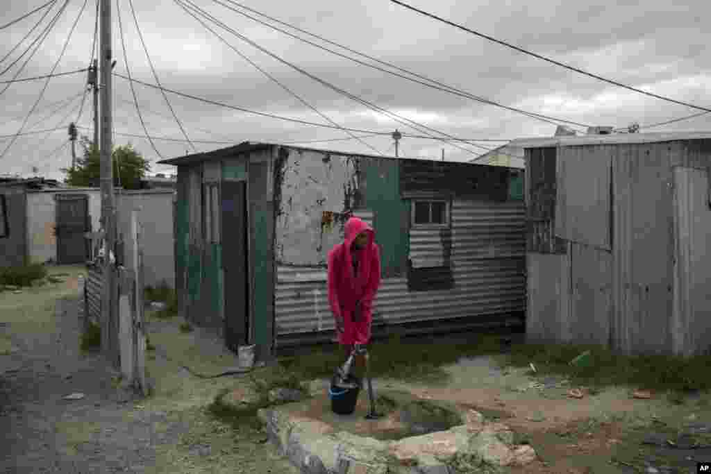 A woman collects water in a settlement near Cape Town.