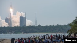 资料照片-人们在海滩上观看长征-5B Y2火箭从中国海南省文昌航天发射中心发射升空。（2021年4月29日）
