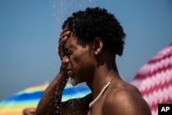 FILE - A man cools off in a shower at Ipanema beach, Rio de Janeiro, Brazil, Sept. 24, 2023, during a summer of record-smashing heat. (AP Photo/Bruna Prado, File)
