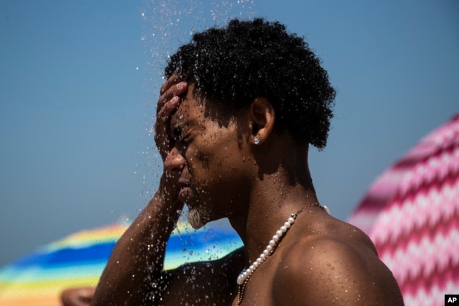 FILE - A man cools off in a shower at Ipanema beach, Rio de Janeiro, Brazil, Sept. 24, 2023, during a summer of record-smashing heat. (AP Photo/Bruna Prado, File)