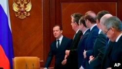 FILE - Russian Prime Minister Dmitry Medvedev, left, arrives to lead a cabinet meeting in the Gorky residence outside Moscow, Russia, April 28, 2018. 
