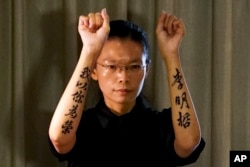 FILE - Lee Ching-yu, wife of Taiwanese activist Lee Ming-Che shows the tattoo words on her arms, which reads "Lee Ming-Che, I'm proud of you" to the reporters at a hotel room after attending her husband's trial at the Yueyang Intermediate People's Court.