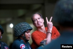 FILE - Australian filmmaker James Ricketson gestures as he leaves the Municipal Court of Phnom Penh, Cambodia, Aug. 16, 2018.