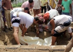 FILE - Mourners lower the body of a man, suspected to have died from the coronavirus disease (COVID-19) in Taiz, Yemen, June 25, 2020.