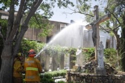 Firefighters hose down hot spots in the aftermath of a morning fire at the San Gabriel Mission, July 11, 2020, in San Gabriel, Calif.