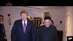 In this image made from video released on March 6, 2019, by North Korean broadcaster KRT, North Korean leader Kim Jong Un, right, smiles while walking with U.S. President Donald Trump for a meeting in Hanoi, Vietnam. 