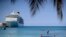 A cruise ship sits docked as tourists jump on a trampoline in Ocho Rios, Jamaica, Friday, Feb. 15, 2019.