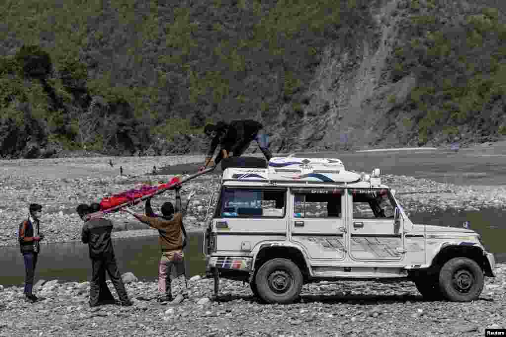 Relatives of Pramila Devi, 36, who died from complications related to the COVID-19, unload her body from a jeep before her cremation, on the banks of the river Ganges in Pauri Garhwal, in the northern state of Uttarakhand, India.